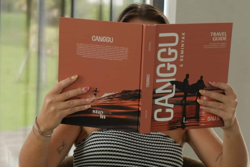 Someone flipping through the Stay In Canggu Travel Guide, showing curated places in Bali