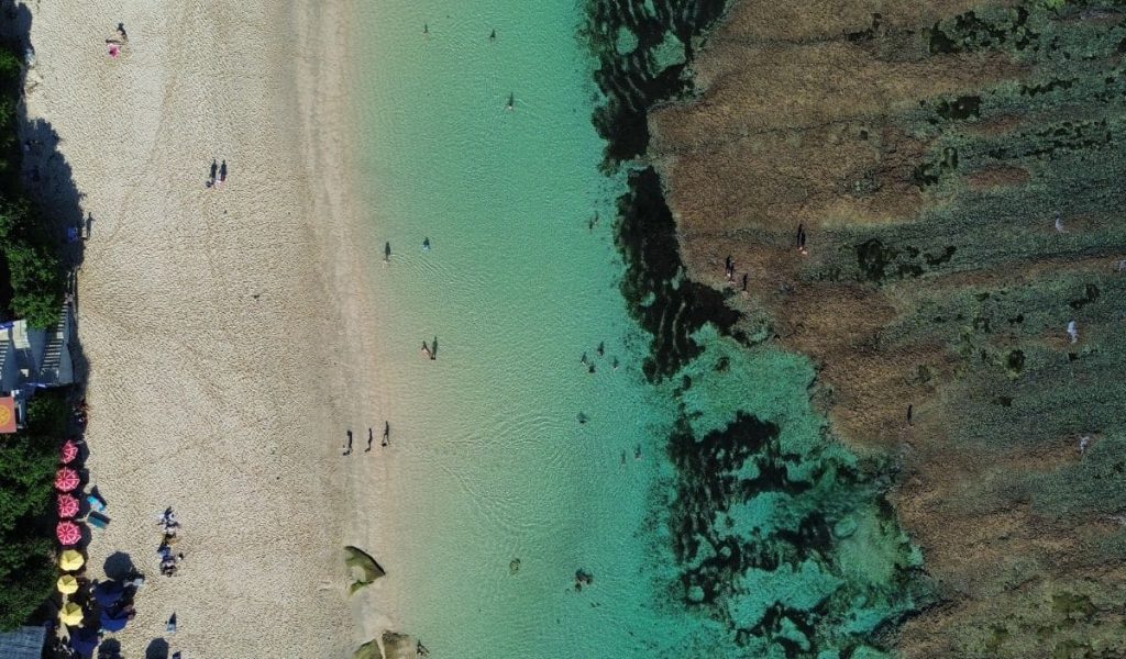 Melasti Beach – Aerial View in Uluwatu Aerial drone view of Melasti Beach in Uluwatu, Bali, with turquoise waters and white sand.