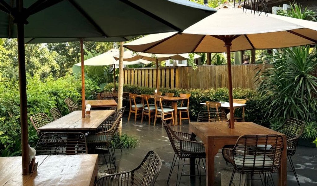 Satu Satu Café Uluwatu – Relaxed Outdoor Dining Outdoor seating area at Satu Satu Café in Uluwatu surrounded by tropical greenery